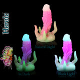 Chaos-Fantasy-Silikondildo in der im Dunkeln leuchtenden Heroic-Farbe, gezeigt bei Tageslicht, im Dunkeln und unter Schwarzlicht