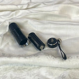 Black UV torch beside white product boxes on silver fabric background