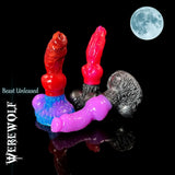 Three fantasy silicone werewolf dildo models in different colour combinations arranged together on a reflective black surface with a full moon in the top corner.