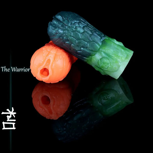 Two custom Ork fantasy silicone masturbators in orange and green-blue colourways, showing the detailed textured entrances and scale patterns