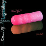 Masturbador de silicona de fantasía Tattooed Elf Legendary en rosa fosforescente, mostrado con luz normal y brillando en la oscuridad.